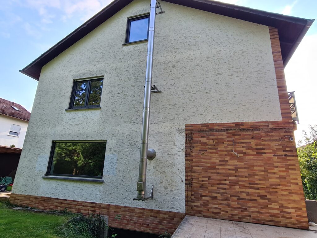 Unrenoviertes Haus mit neuen Fenstern, Rückansicht des Gebäudes vor Beginn der Sanierungsarbeiten.
